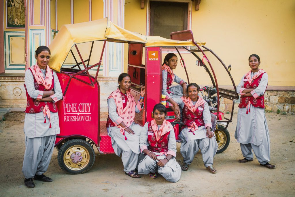 Gruppe indischer Frauen posieren mit einer pinken Rickshaw