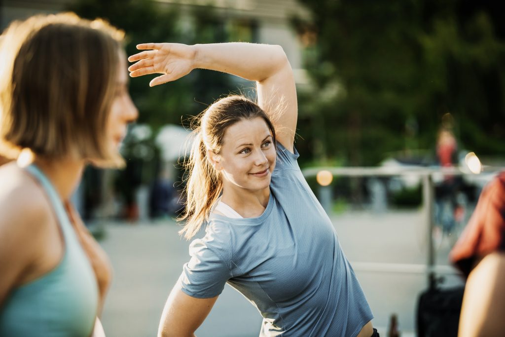 Eine Gruppe von Frauen wärmt sich gemeinsam draußen auf, bevor sie einen Lauf durch die Stadt machen.