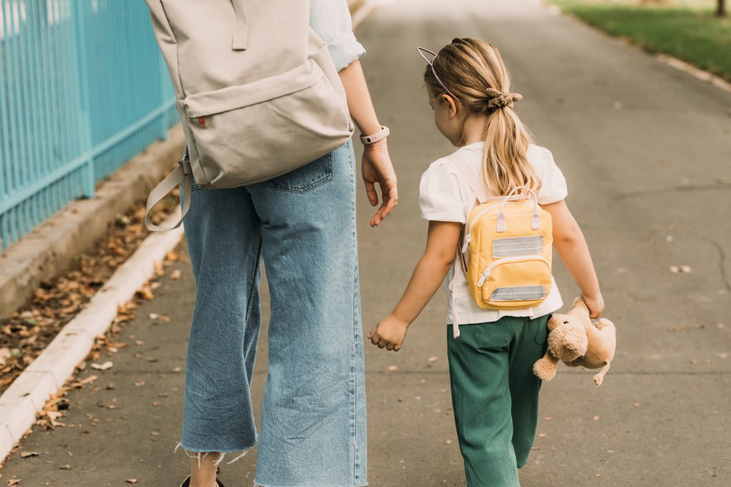 Mutter und Kind gehen gemeinsam zur Schule.