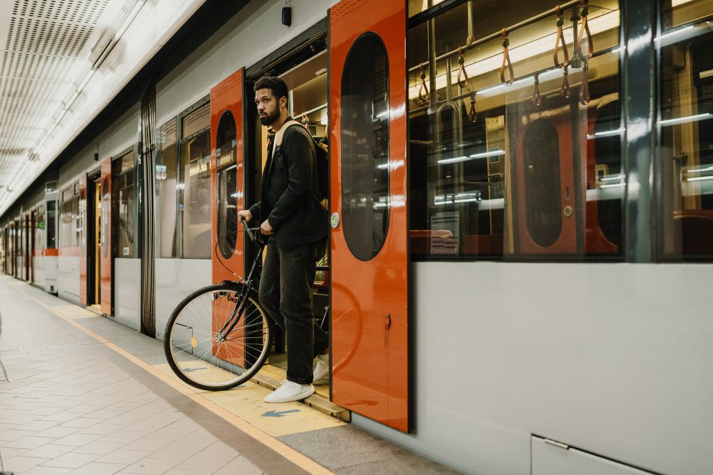 Mann mit Fahrrad auf U-Bahn-Station, Aussteigen aus U-Bahn-Zug. Alleinstehender Mann, der mit öffentlichen Verkehrsmitteln und seinem Fahrrad in der Stadt unterwegs ist. Nachhaltiger Lebensstil eines alleinstehenden Mannes.