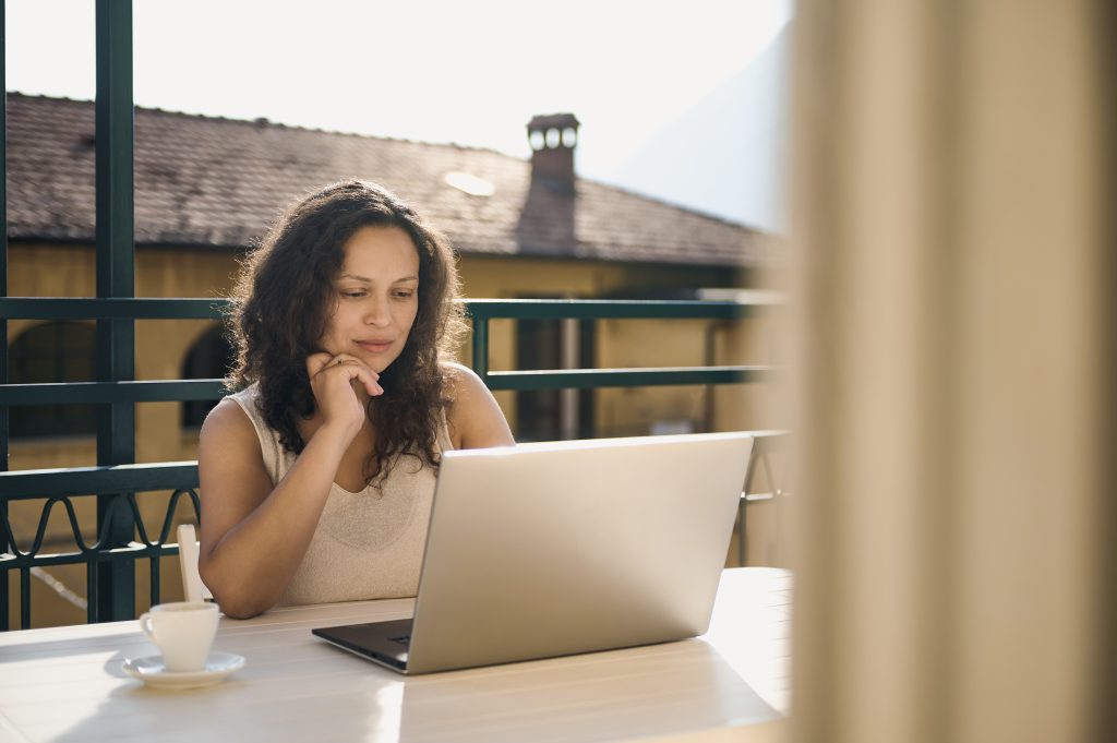 Geschäftsfrau, Unternehmerin, freiberufliche Telearbeiterin, die von zu Hause aus online am Laptop arbeitet, am Tisch auf dem Balkon sitzend. Menschen. Geschäft. Lebensstil. Konzept der Telearbeit