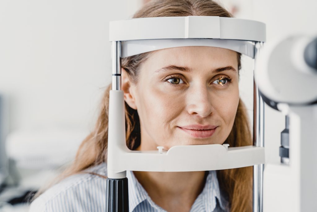 Nahaufnahme einer jungen, lächelnden Patientin bei einer Augenuntersuchung. Untersuchung der Augengesundheit. Besuch beim Augenarzt. Sehkraftverlust, Myopie, Kataraktprävention;