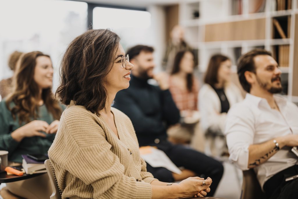 Lächelnde Frau, die an einem professionellen Workshop mit Kollegen in einer modernen Büroumgebung teilnimmt und Engagement und Teamarbeit vermittelt