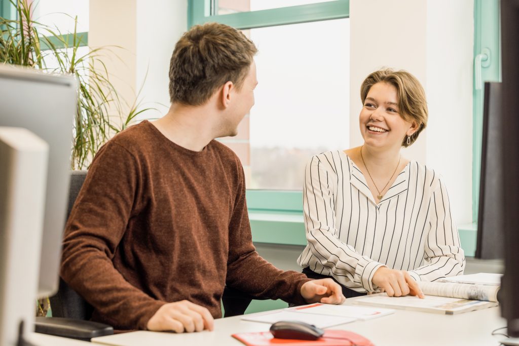 junge Menschen sitzen in einem Büro und schauen sich an